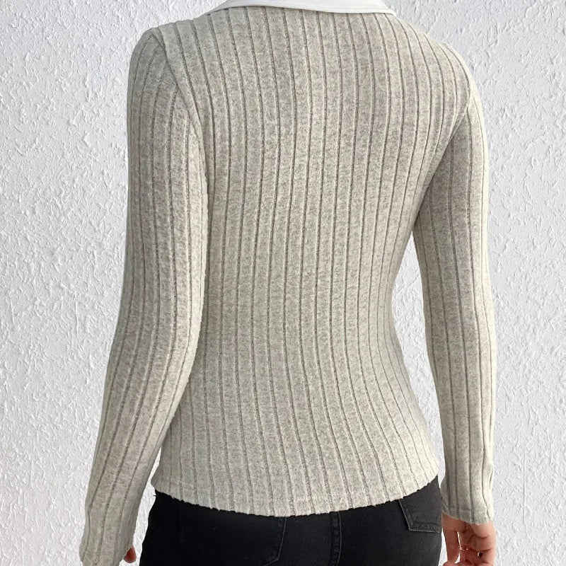 Woman wearing a light gray ribbed knit bodysuit with a white collar and black jeans.