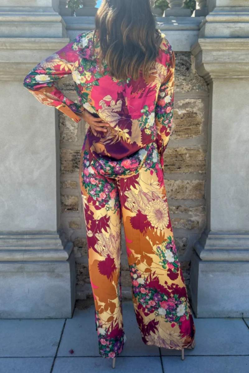 Woman in floral satin pantsuit standing on patio