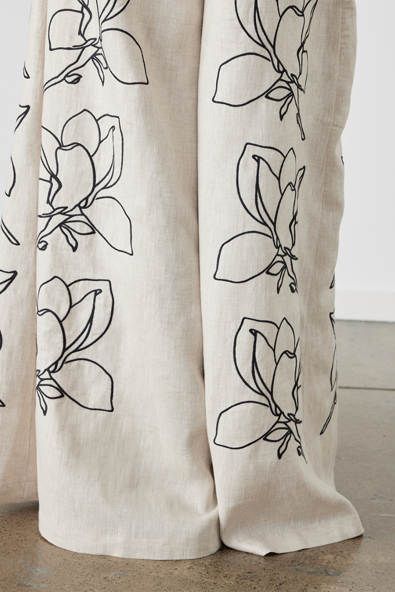 Woman wearing linen pant set with black magnolia embroidery