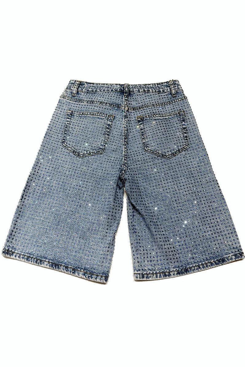 Woman wearing light wash denim bermuda shorts with sparkly embellishments
