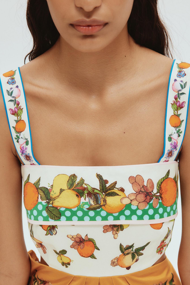 Woman in colorful citrus print mini dress holding fishing rod