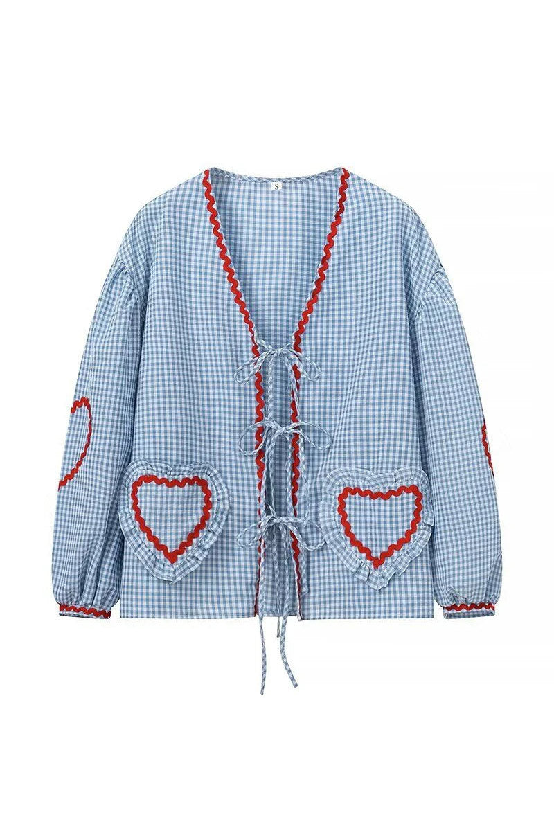 Woman in pink gingham blouse with heart pockets and denim shorts