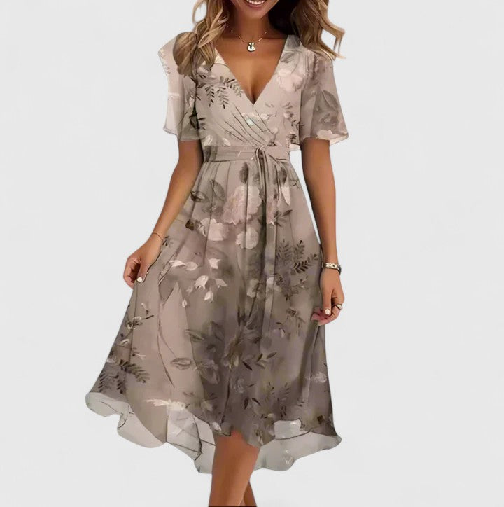 Light Brown - A woman wearing a V-neck midi dress featuring a vibrant blue and green abstract mosaic print, short flutter sleeves, and a flowing A-line skirt.