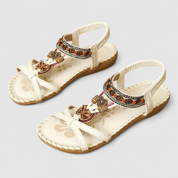 White Athena - Faux-leather flat slingback sandals featuring a beaded medallion centerpiece, embroidered instep strap, and contrast stitching along the sole edge.
