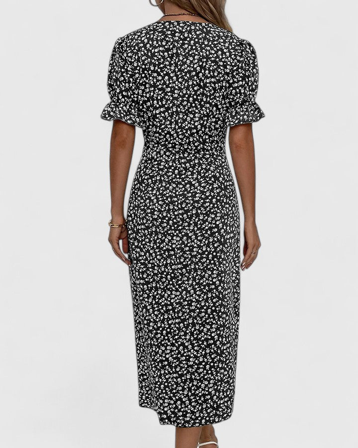 Black - A woman wearing a green midi dress with a white ditsy floral print, featuring short puff sleeves, a V-neckline, and decorative side buttons with a ruched wrap skirt.