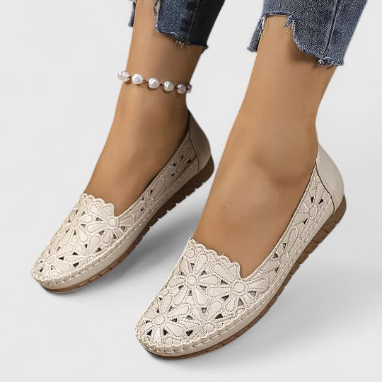 Beige - Women's slip-on loafers featuring a faux-leather upper with detailed floral cutouts, scalloped edges, and a textured flat sole.