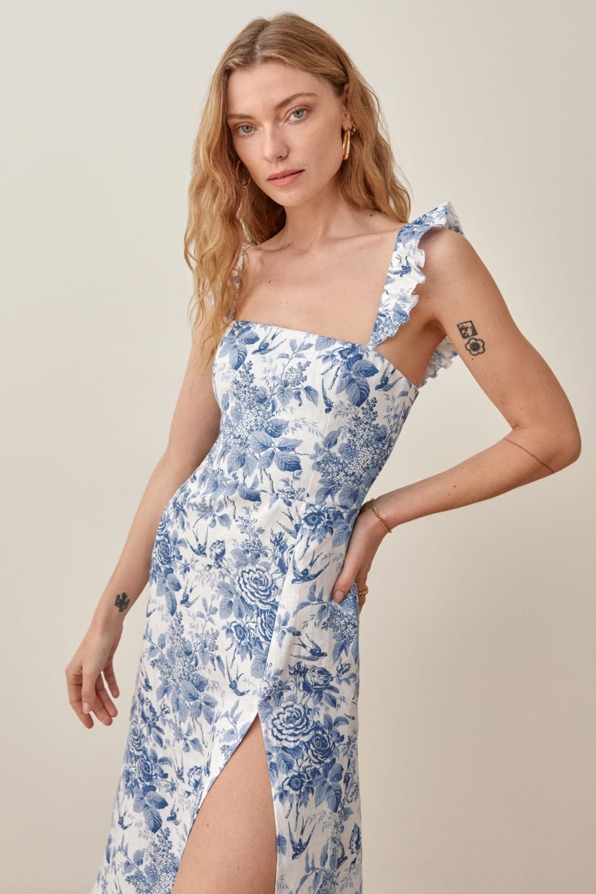 Woman wearing blue and white floral linen midi dress with ruffle straps and thigh slit
