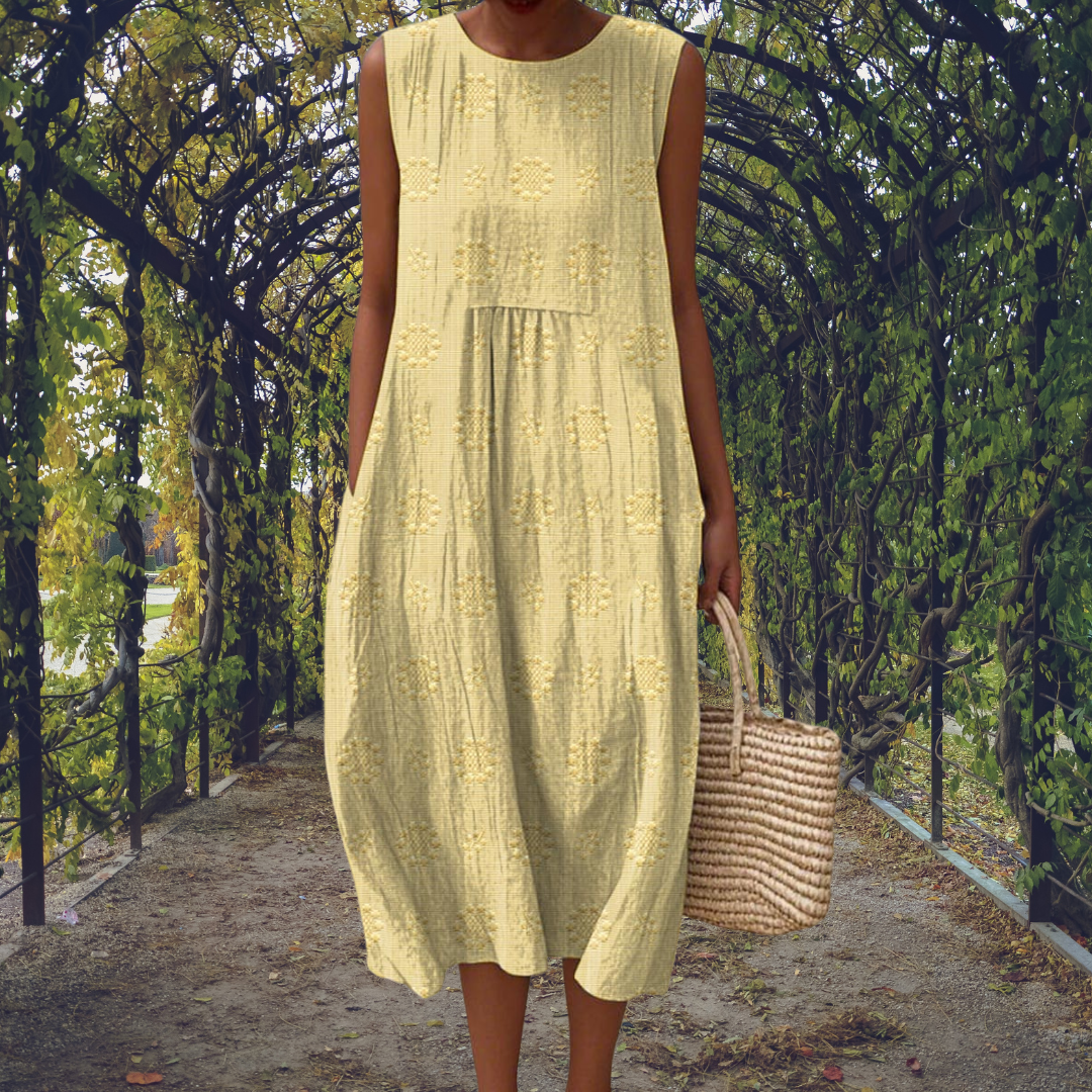 Light Yellow - Woman wearing a sleeveless, A-line midi sundress featuring an all-over 3D floral applique pattern and side seam pockets, standing on a gravel path.