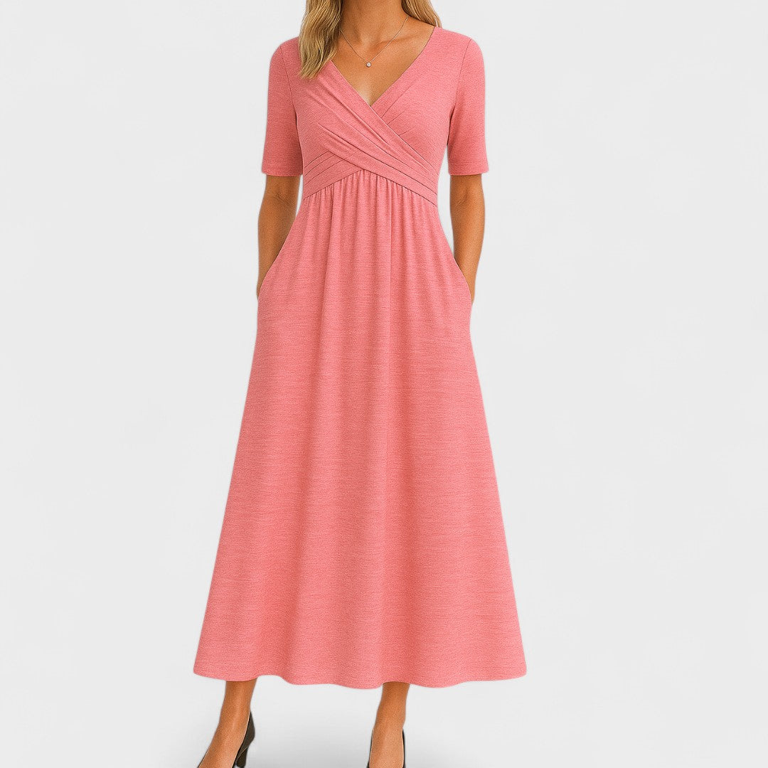 Pink - A woman wearing a heather gray jersey knit midi dress featuring a surplice V-neckline, ruched wrap bodice, short sleeves, and a flowy A-line skirt with side pockets.