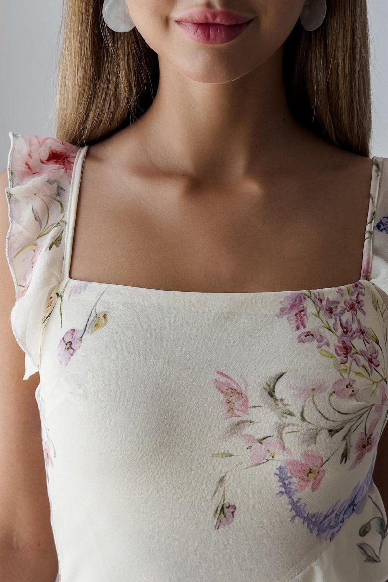 A woman wearing a floral chiffon dress with ruffles.