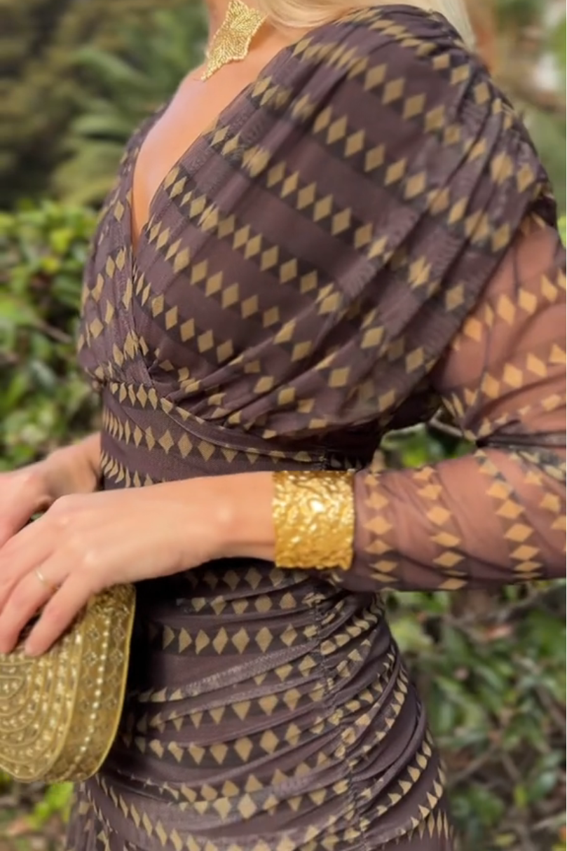Woman in brown chiffon dress with gold accessories