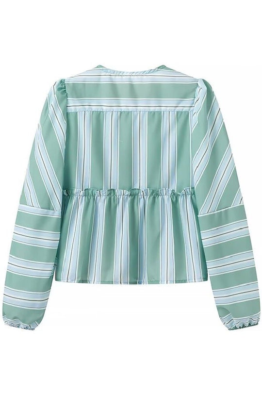 Woman in striped green cotton shorts set holding a drink.