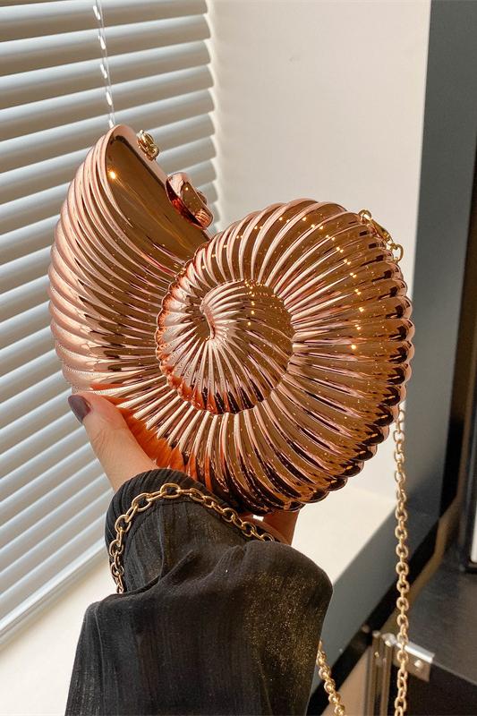 Three metallic shell-shaped clutches in silver, gold, and rose gold