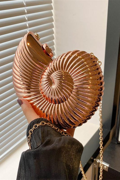 Three metallic shell-shaped clutches in silver, gold, and rose gold