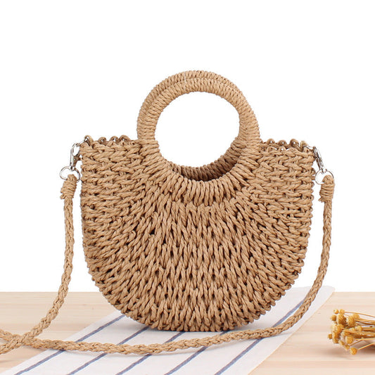 Front view of tan woven straw half-moon bag with round handle and braided shoulder strap