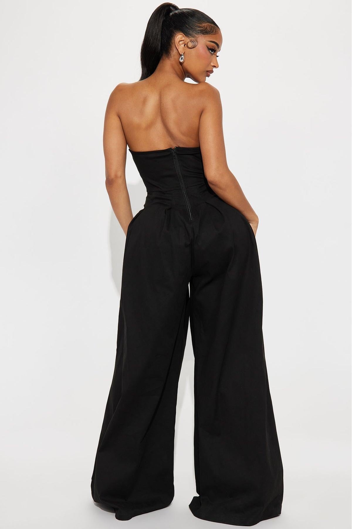 Woman in black one-shoulder woven jumpsuit with gold buttons