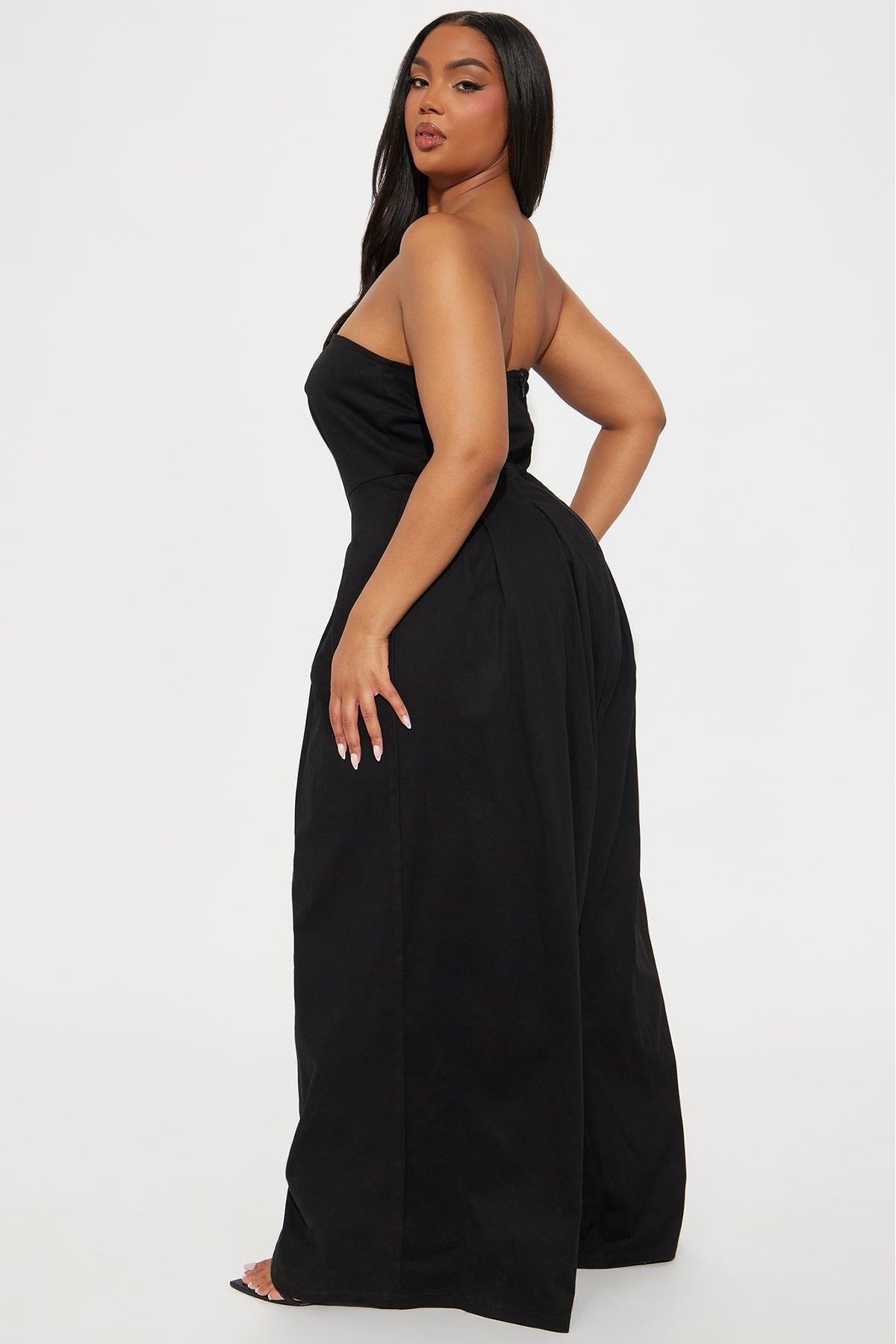 Woman in black one-shoulder woven jumpsuit with gold buttons