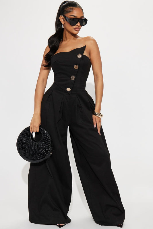 Woman in black one-shoulder woven jumpsuit with gold buttons