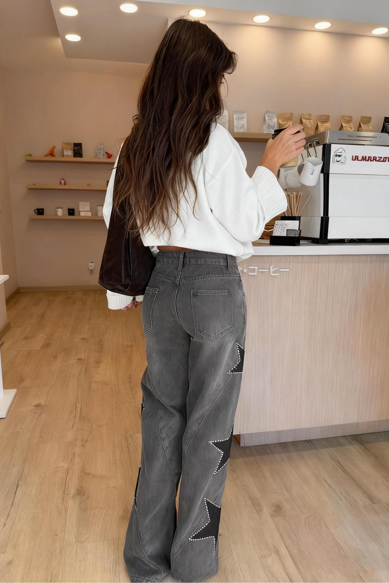 Woman wearing light wash wide leg jeans with star appliqués