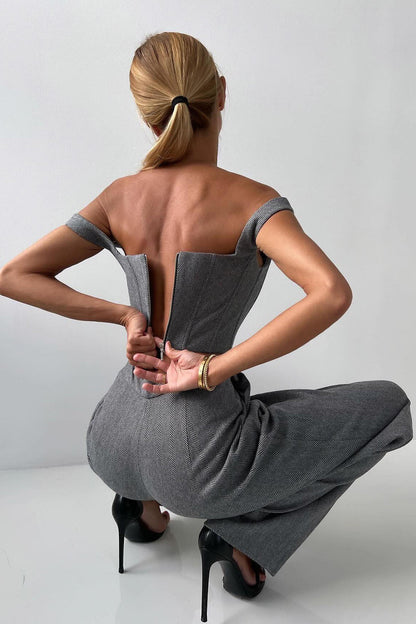 Woman in gray herringbone corset top, wide leg pants, and blazer