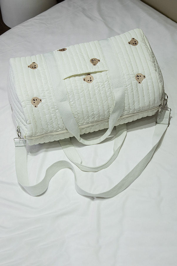 Off-white quilted duffle bag with teddy bear embroidery hanging on a coat rack