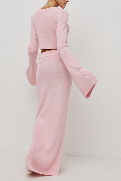 Woman wearing pink ribbed knit cardigan and skirt set with high slit.
