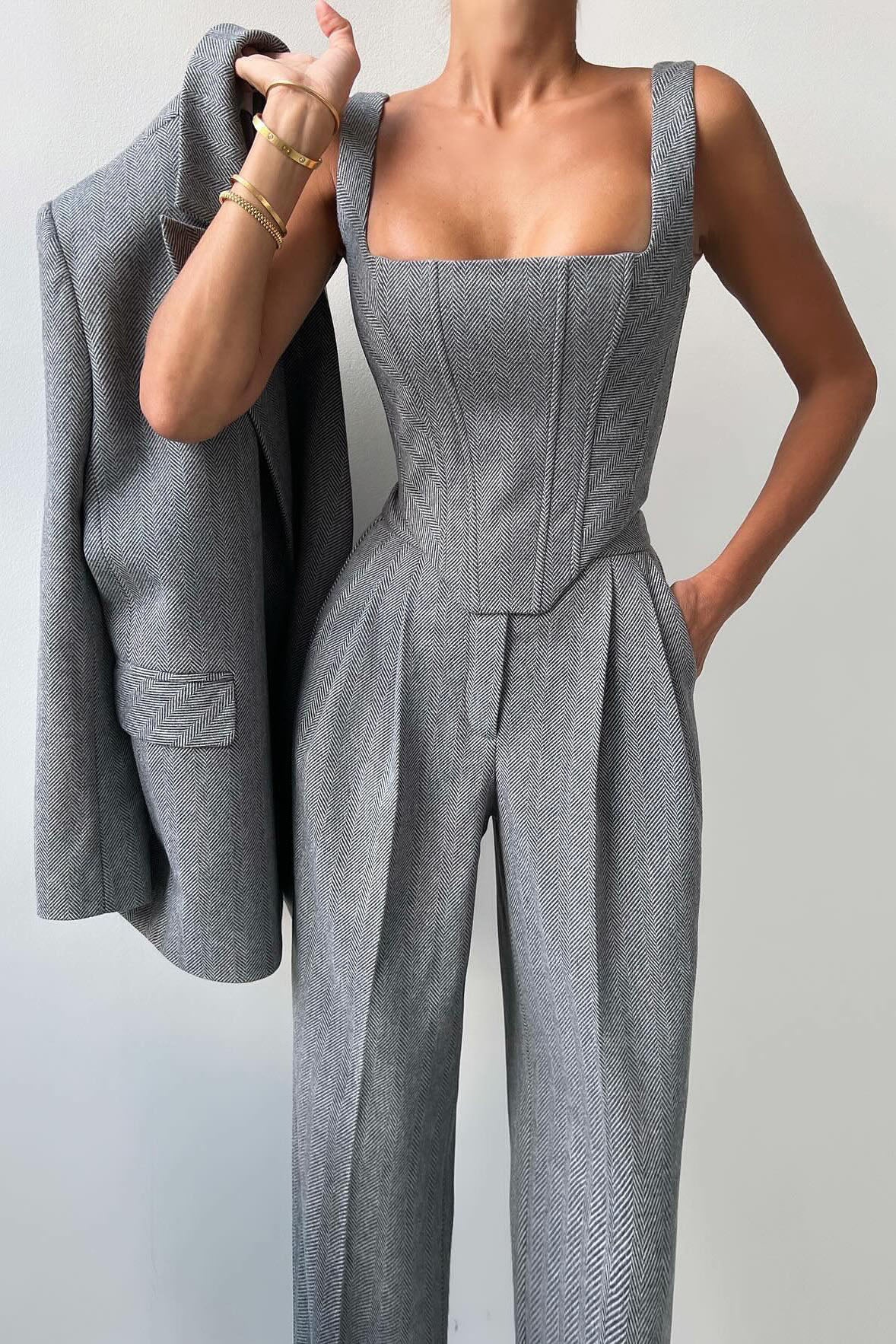 Woman in gray herringbone corset top, wide leg pants, and blazer