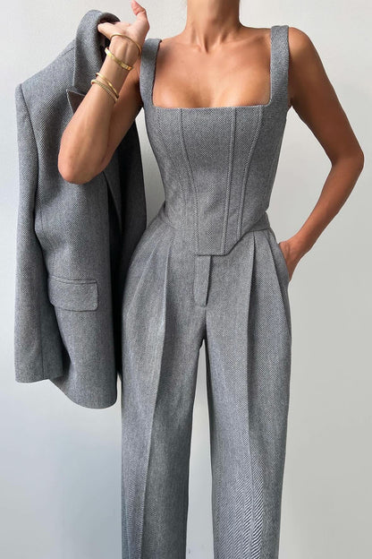 Woman in gray herringbone corset top, wide leg pants, and blazer