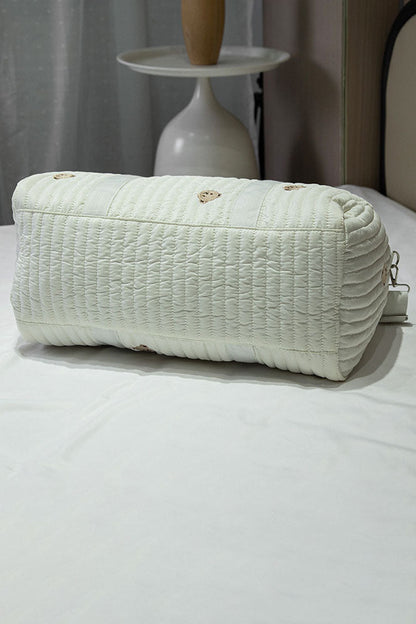 Off-white quilted duffle bag with teddy bear embroidery hanging on a coat rack