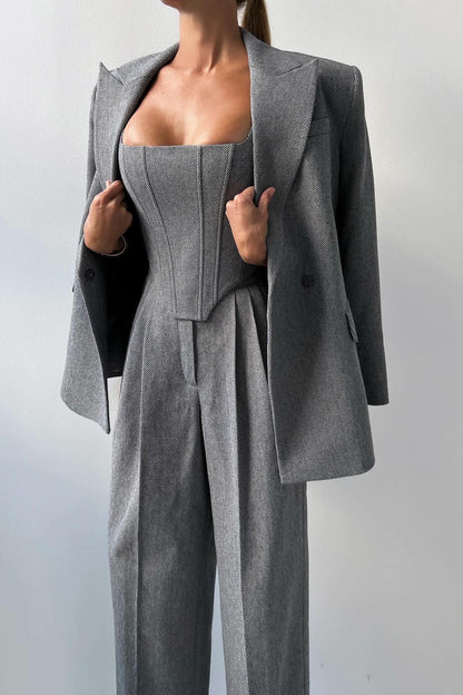 Woman in gray herringbone corset top, wide leg pants, and blazer