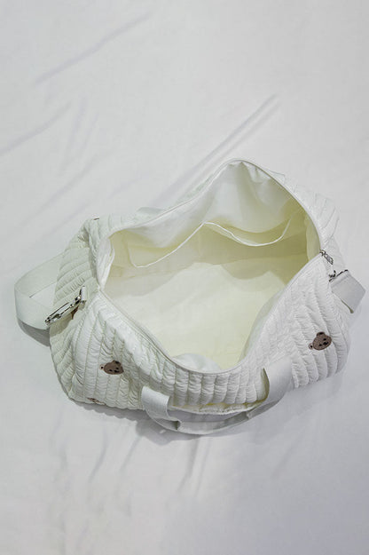 Off-white quilted duffle bag with teddy bear embroidery hanging on a coat rack