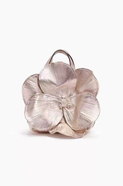 Woman in pink floral chiffon dress holding a red flower-shaped purse