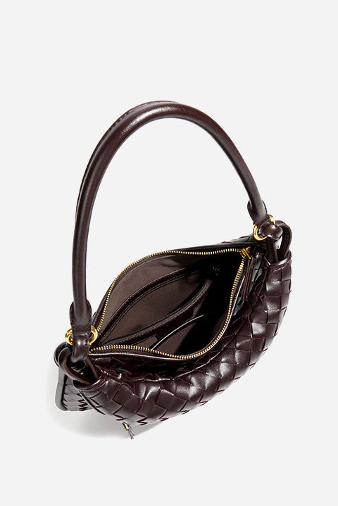 Woman holding dark brown woven leather hobo bag