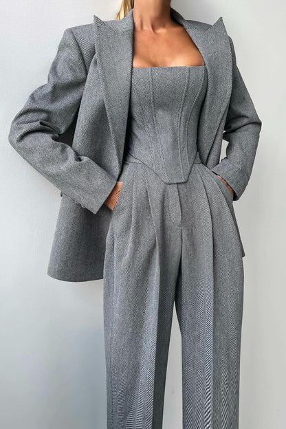 Woman in gray herringbone corset top, wide leg pants, and blazer