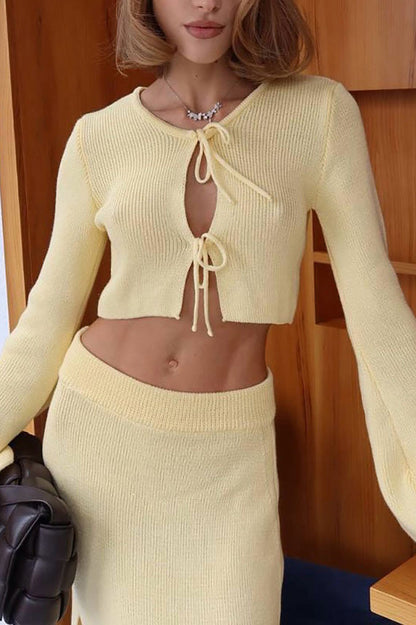 Woman wearing pink ribbed knit cardigan and skirt set with high slit.