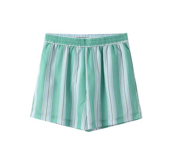 Woman in striped green cotton shorts set holding a drink.
