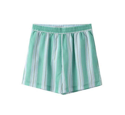 Woman in striped green cotton shorts set holding a drink.
