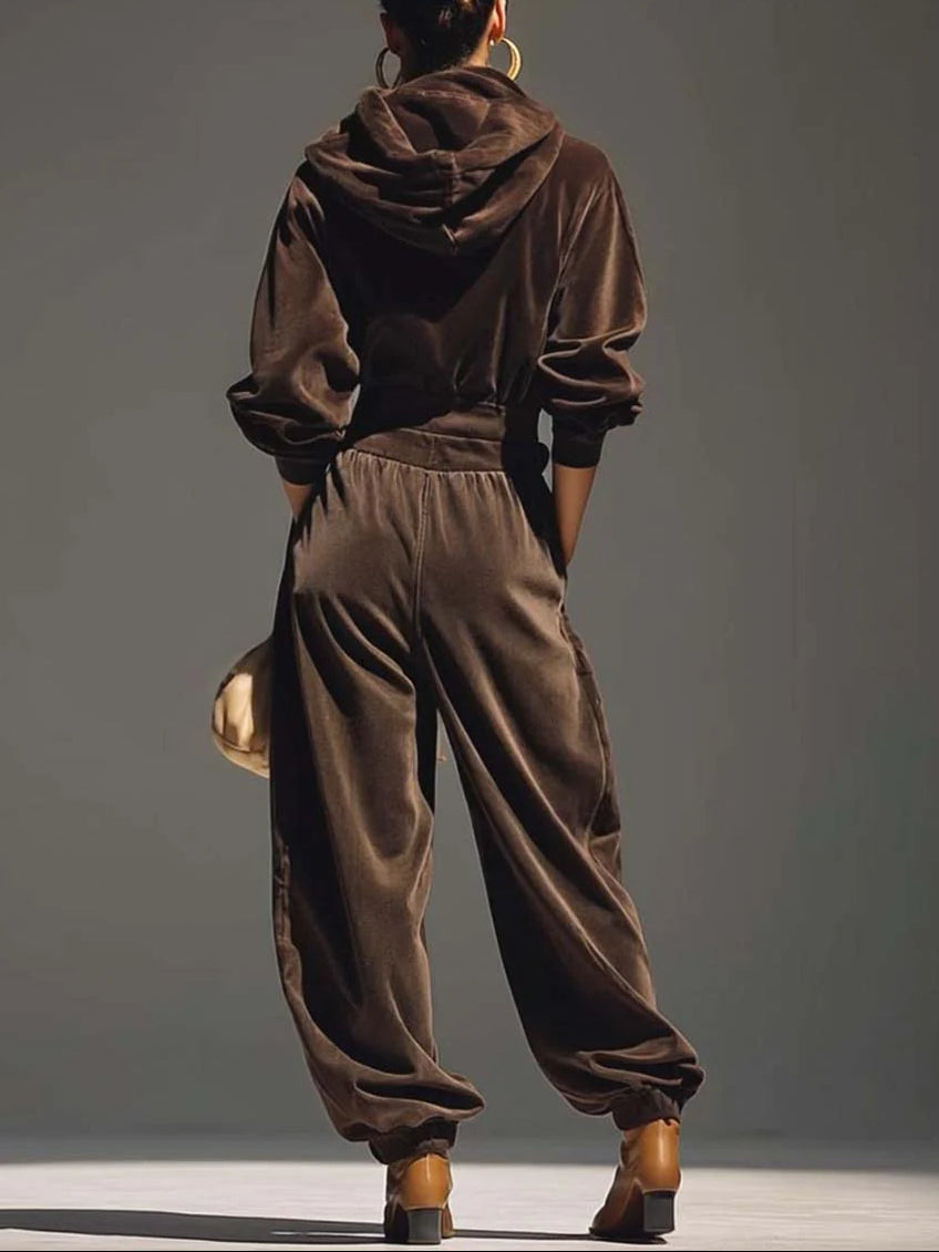 Woman wearing brown velvet cowl neck top and wide leg pants with cream-colored purse.