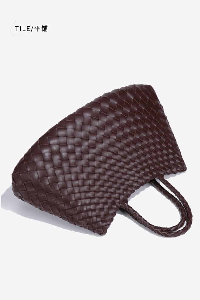 Woman holding brown woven tote bag