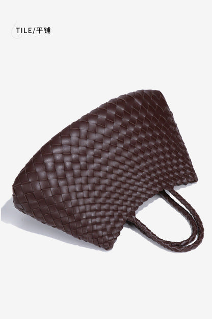Woman holding brown woven tote bag