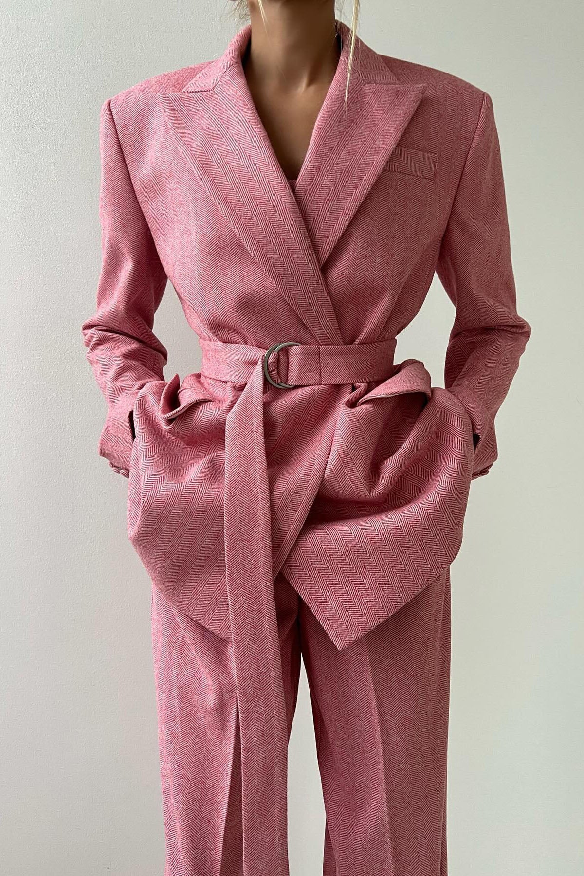 Woman in gray herringbone corset top, wide leg pants, and blazer