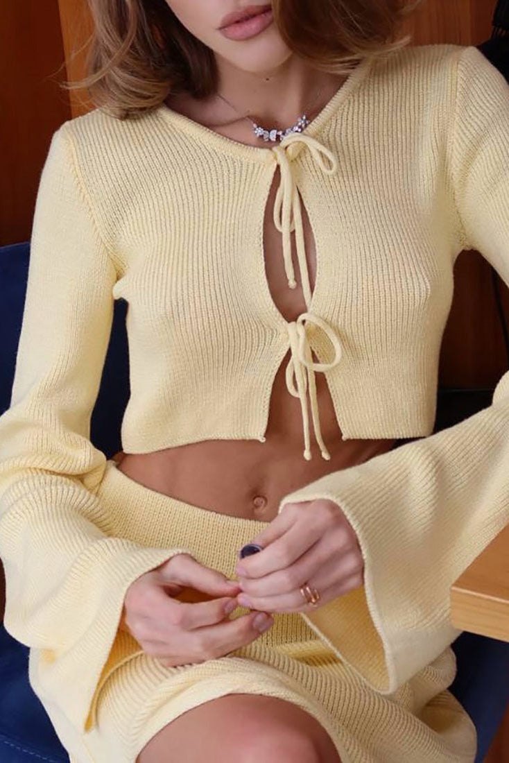Woman wearing pink ribbed knit cardigan and skirt set with high slit.