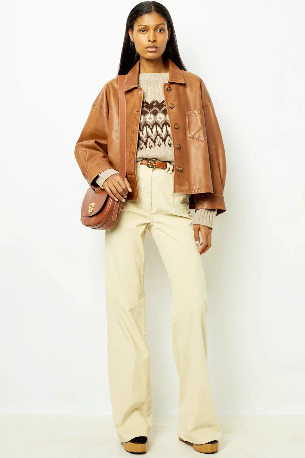 Woman wearing tan leather jacket and patterned sweater