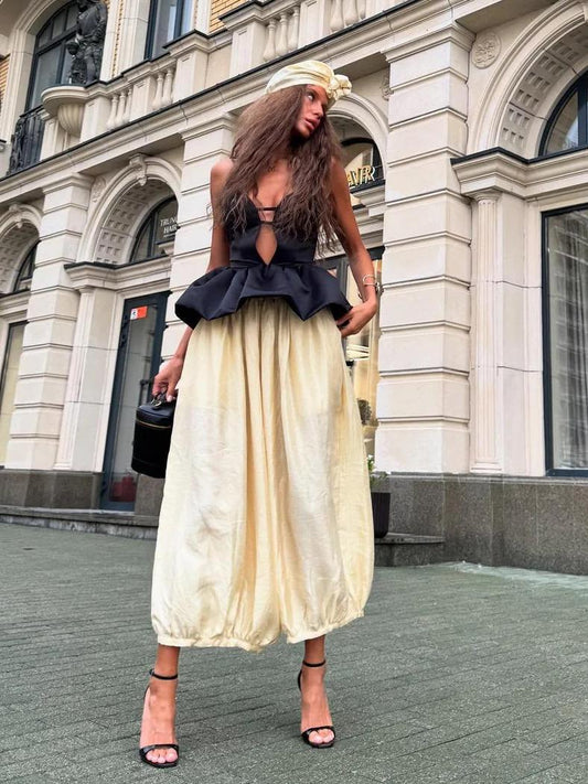 Woman in black peplum top with ivory balloon skirt and heels.