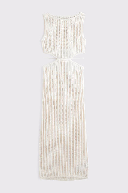 Woman wearing a long, off-white crochet knit dress with waist cutouts.