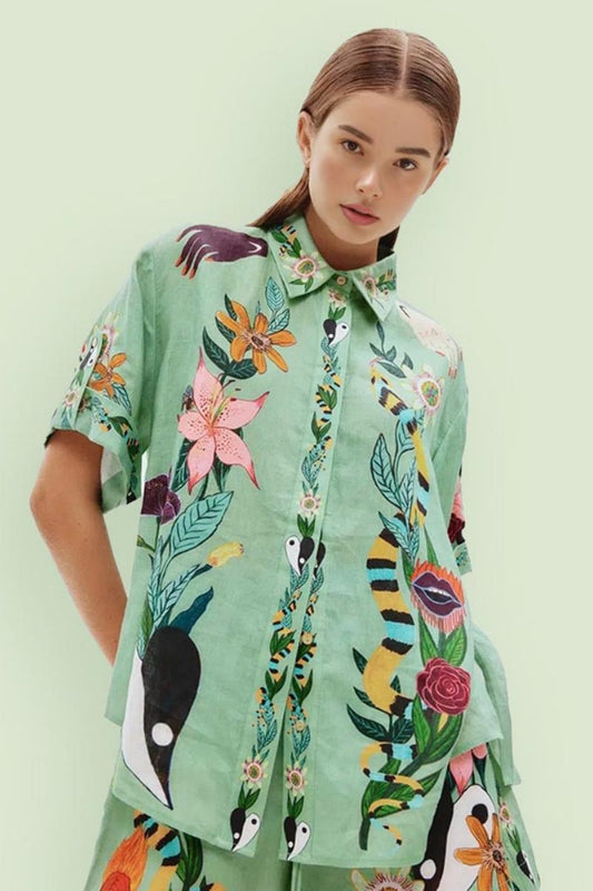 Woman wearing a light green linen shirt with floral and snake print