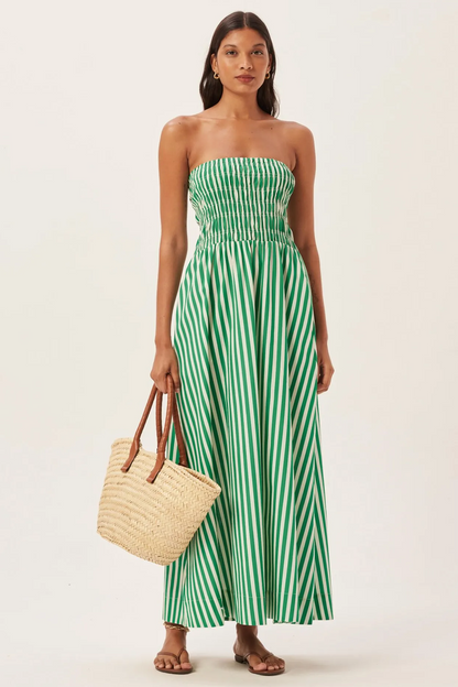 Woman in green and white striped strapless maxi dress holding straw tote bag