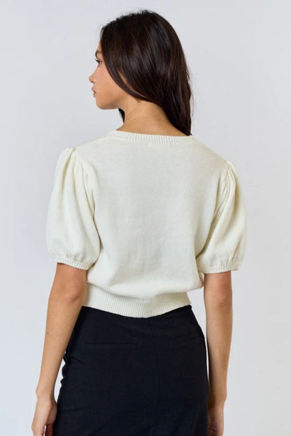 Woman wearing ivory ribbed knit cardigan with black bows