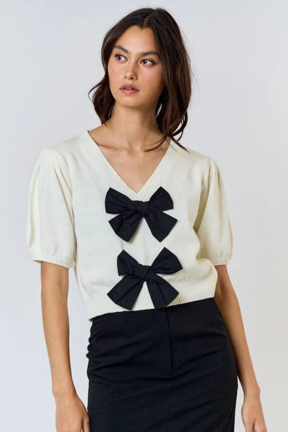 Woman wearing ivory ribbed knit cardigan with black bows