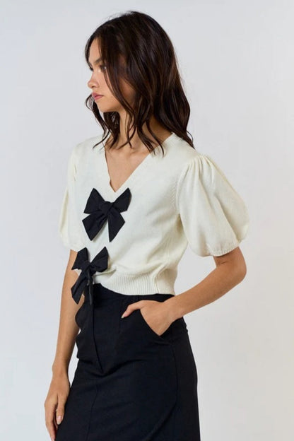Woman wearing ivory ribbed knit cardigan with black bows